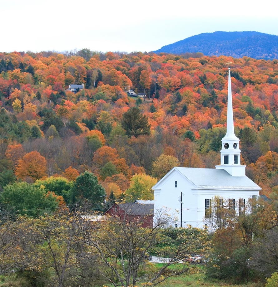 A small rural church is nestled among autumn trees