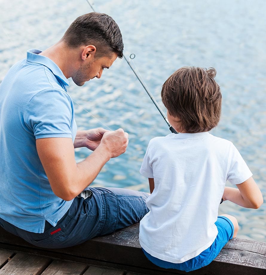 A man baits a hook while a young boy looks on