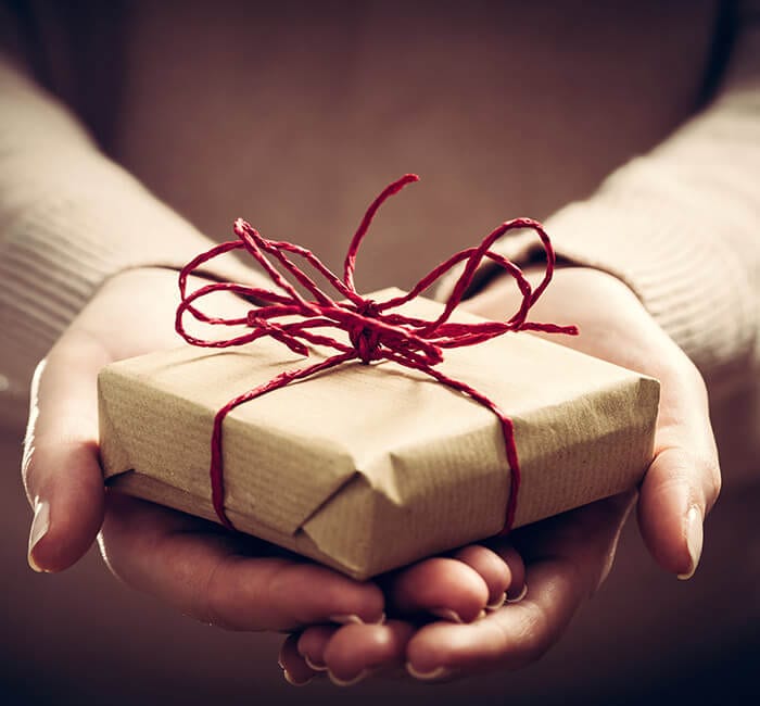 Hands holding a small gift with red ribbon